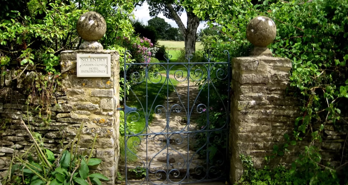 Elegant garden entrance with ornate iron gate and stone pillars