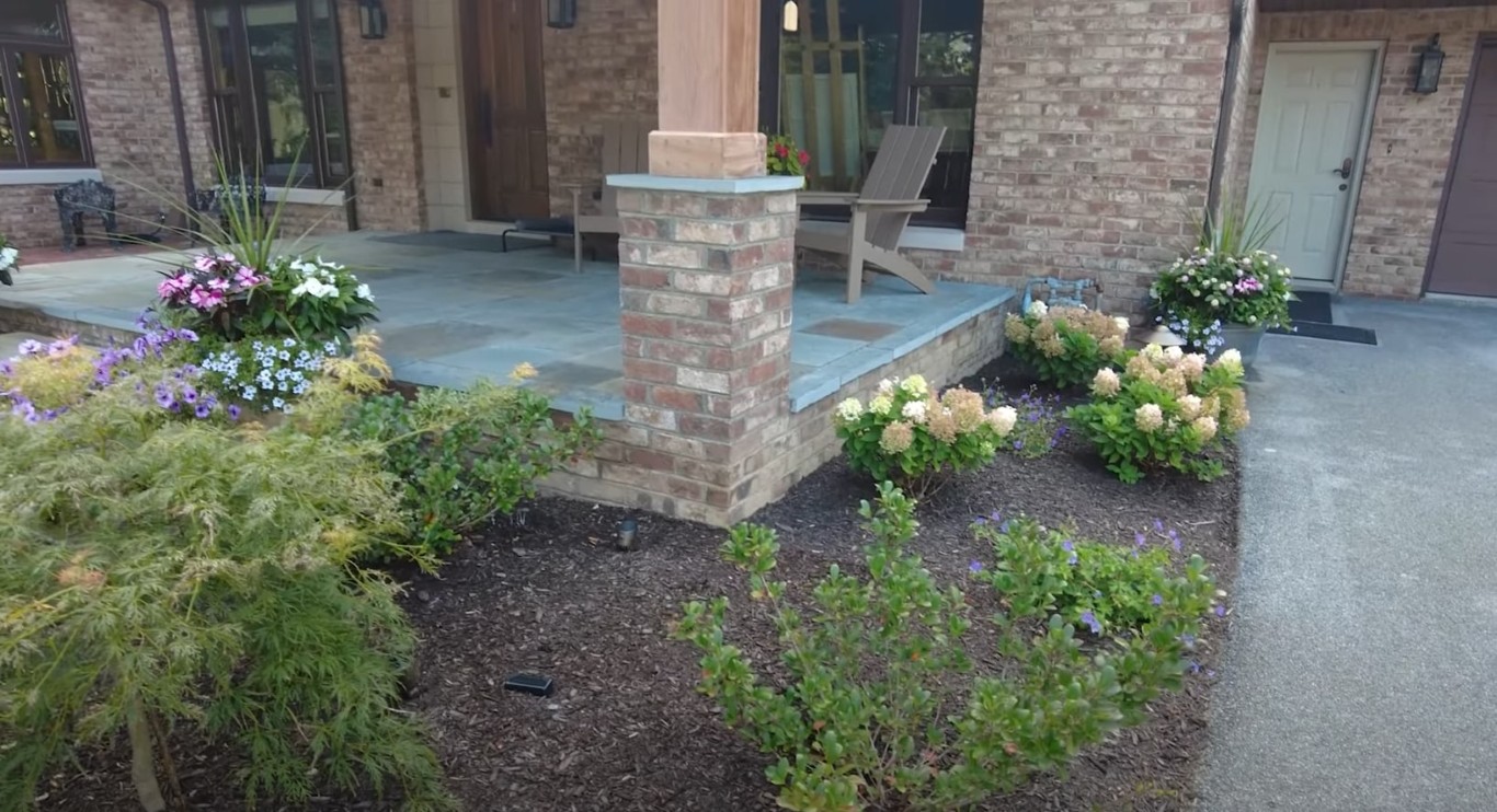 Decorative patio with brick pillars and colorful flower beds